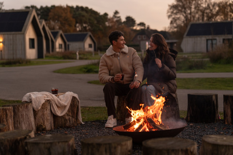 Couple enjoys a campfire evening at Unbrick One | Sauna and Pool at De Weelderik in the Netherlands.