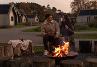 Couple enjoys a campfire evening at Unbrick One | Sauna and Pool at De Weelderik in the Netherlands.