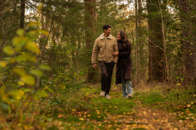 Una pareja camina por un bosque cerca de Unbrick One | Sauna and Pool, rodeada de árboles y naturaleza.