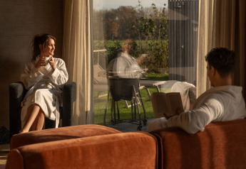 Due persone si rilassano in accappatoio all’interno di Unbrick One Lodge, De Weelderik, Paesi Bassi, al tramonto.