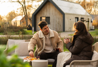 Koppel geniet van drankjes en hapjes buiten bij Unbrick One | Sauna and Pool bij De Weelderik, Nederland.