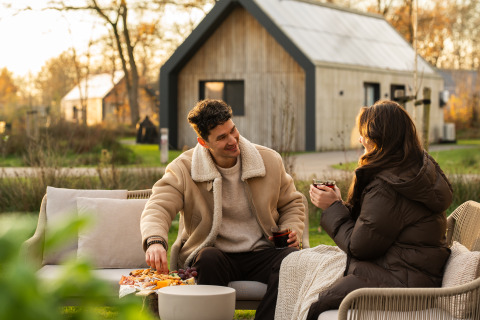 Pareja disfrutando bebidas y aperitivos al aire libre en Unbrick One | Sauna and Pool en De Weelderik, Países Bajos.