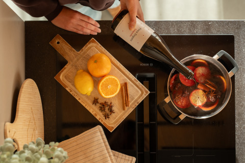 Persona che versa vino in una pentola con agrumi e spezie a Unbrick One | Sauna and Pool, De Weelderik, Paesi Bassi.