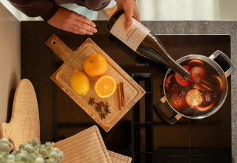 Person pouring wine into a pot with citrus fruits and spices at Unbrick One | Sauna and Pool, De Weelderik, Netherlands.