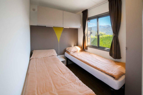 Twee eenpersoonsbedden met beige lakens in een lichte kamer van «Next XL» Superiore, Vacanze Glamping Boutique, Italië.