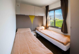 Twee eenpersoonsbedden met beige lakens in een lichte kamer van «Next XL» Superiore, Vacanze Glamping Boutique, Italië.