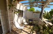 Sunny wooden terrace with two lounge chairs and a grill at the Next XL Superiore lodge, Vacanze Glamping Boutique, Italy.
