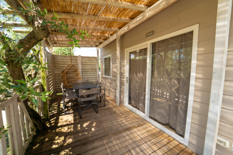 Houten terras met eettafel, stoelen en hangstoel bij Next XL Superiore lodge, Vacanze Glamping Boutique, Italië.