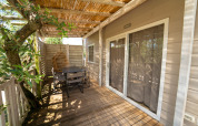 Wooden terrace with dining table, chairs, and hanging chair at Next XL Superiore lodge, Vacanze Glamping Boutique, Italy.
