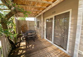 Houten terras met eettafel, stoelen en hangstoel bij Next XL Superiore lodge, Vacanze Glamping Boutique, Italië.