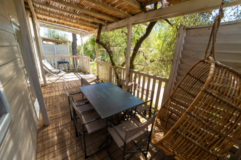 Overdekt terras van de Next XL Superiore-lodge bij Vacanze Glamping Boutique, Italië, met tafel en hangstoel.