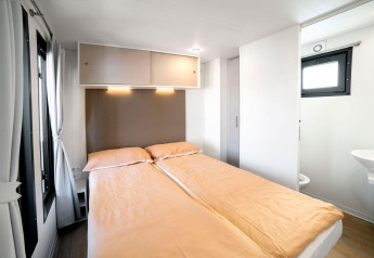 Dormitorio moderno con cama doble y baño integrado en Cottage Next 1/5 pers. de Vacanze Glamping Boutique, Italia.