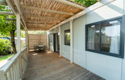 Covered wooden terrace with outdoor dining area at Cottage Next lodge, Vacanze Glamping Boutique, Italy.