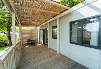 Træterrasse med overdækning og havemøbler ved Cottage Next lodge på Vacanze Glamping Boutique i Italien.