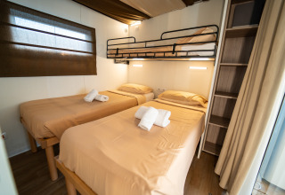 Interior de una habitación Cottage Clever en Vacanze Glamping Boutique Italia, con tres camas y estantería.