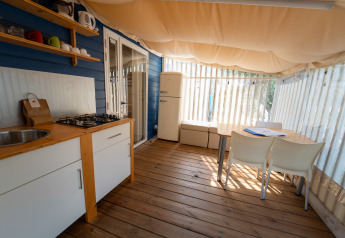 Cocina y comedor en Cottage Clever, Vacanze Glamping Boutique en Italia, con suelo de madera y toldo.