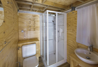 Badkamer met houten muren, douche, toilet en wastafel in Airlodge 2.0 bij Vacanze Glamping Boutique, Italië.
