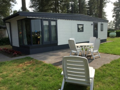 Zonnige buitenruimte aan de Sun Lodge met terras, tuin en witte stoelen voor het vakantieverblijf.