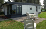 Zonnige buitenruimte aan de Sun Lodge met terras, tuin en witte stoelen voor het vakantieverblijf.