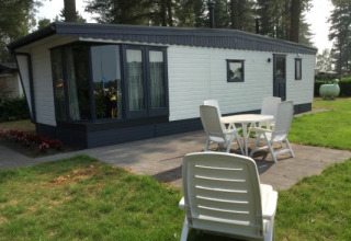 Zonnige buitenruimte bij Sun Lodge met terras, tuin en witte tuinmeubels bij het vakantieverblijf.