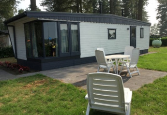 Zonnige buitenruimte aan de Sun Lodge met terras, tuin en witte stoelen voor het vakantieverblijf.