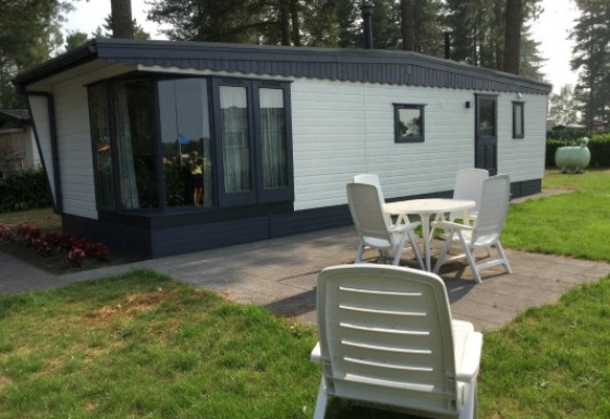 Zonnige buitenruimte aan de Sun Lodge met terras, tuin en witte stoelen voor het vakantieverblijf.