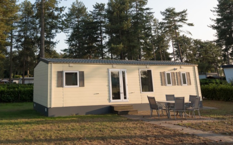Sun Lodge Comfort ad Arden Parks Tulderheyde, Belgio, con mobili da esterno e pini alti sullo sfondo.