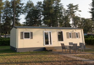 Sun Lodge Comfort ad Arden Parks Tulderheyde, Belgio, con mobili da esterno e pini alti sullo sfondo.