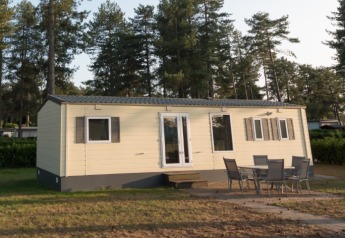 Sun Lodge Comfort ad Arden Parks Tulderheyde, Belgio, con mobili da esterno e pini alti sullo sfondo.