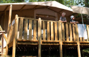 Two people stand on the wooden deck of a Lodge Tent Deluxe at Vacanze Glamping Boutique in Italy.