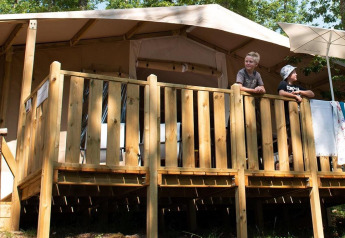 Due persone sulla veranda in legno di una Lodge Tent Deluxe presso Vacanze Glamping Boutique in Italia.