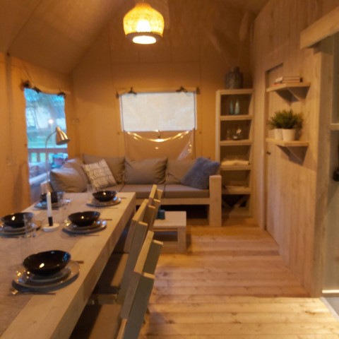 Interior de la tienda safari Ranger Lodge en Petite Suisse, Bélgica, con zona de comedor y salón.