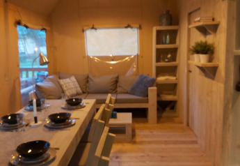 Interior view of the Ranger Lodge safari tent at Petite Suisse, Belgium, featuring dining and lounge area.