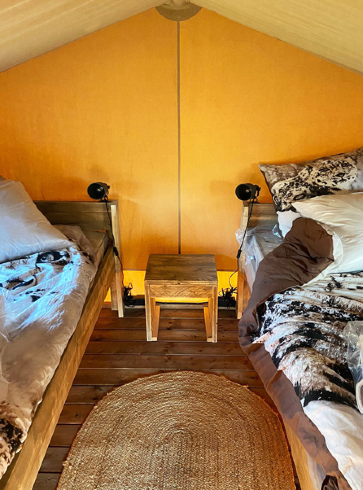 Interieur van een safaritent met twee bedden en houten meubels op Bivouac Comfort, Camping Le Val de Cesse.