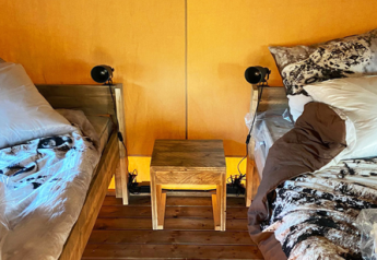 Interno di una tenda safari con due letti e mobili in legno al Bivouac Comfort, Campeggio Le Val de Cesse, Francia.