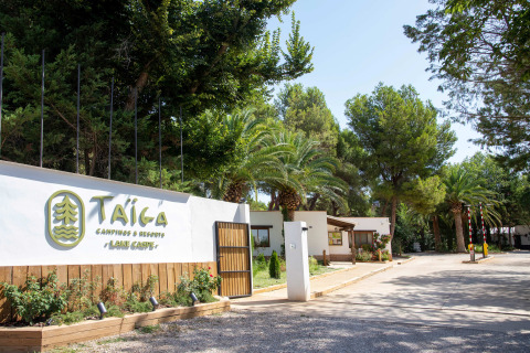 Ingang van vakantiepark TAIGA Lake Caspe in Aragón, Spanje, met veel bomen en mooie beplanting eromheen.