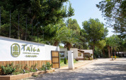 Ingresso del villaggio vacanze TAIGA Lake Caspe in Aragona, Spagna, circondato da alberi verdi lussureggianti.