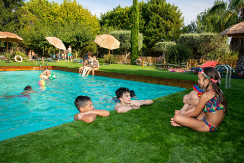 Kinderen en volwassenen genieten aan het zwembad bij TAIGA Lake Caspe vakantiepark in Aragón, Spanje.