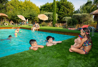 Kinderen en volwassenen genieten aan het zwembad bij TAIGA Lake Caspe vakantiepark in Aragón, Spanje.