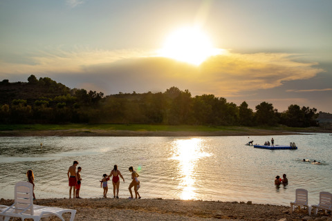 Coucher de soleil au TAIGA Lake Caspe, parc de vacances en Aragón, Espagne, avec personnes au bord de l’eau.