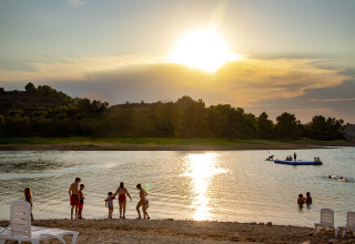 Zonsondergang aan TAIGA Lake Caspe vakantiepark in Aragón, Spanje, mensen relaxen aan water en strand.
