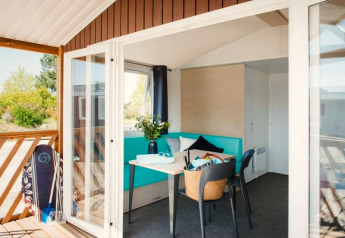 Lichte, moderne Beach Lodge bij Arden Parks Tulderheyde in België met terras en surfplank buiten.