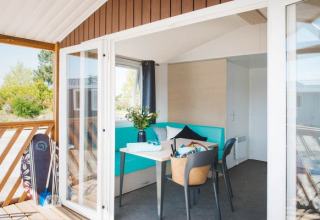 Luminosa e moderna Beach Lodge ad Arden Parks Tulderheyde, Belgio, con terrazza e tavola da surf fuori.