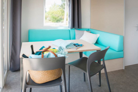 Area soggiorno luminosa e moderna con divano turchese, tavolo e sedie alle Beach Lodges, Arden Parks Tulderheyde.