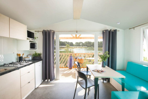 Cucina e soggiorno luminosi nelle Beach Lodges di Arden Parks Tulderheyde, Belgio, con vista sul lago.