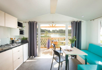 Cucina e soggiorno luminosi nelle Beach Lodges di Arden Parks Tulderheyde, Belgio, con vista sul lago.