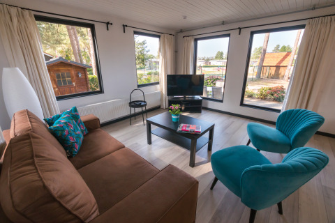 Woonruimte in Luxe Lodges van Arden Parks Tulderheyde, België, met panoramische ramen en eigentijds meubilair.