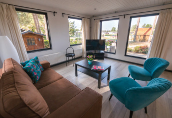 Woonruimte in Luxe Lodges van Arden Parks Tulderheyde, België, met panoramische ramen en eigentijds meubilair.