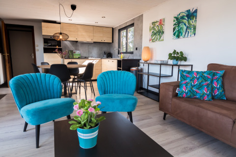 Trendy woonkamer in Luxe Lodges bij Arden Parks Tulderheyde, België, met kleurrijke blauwe stoelen.