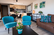 Zona living moderna nei Luxe Lodges di Arden Parks Tulderheyde, Belgio, con poltrone blu vivaci.